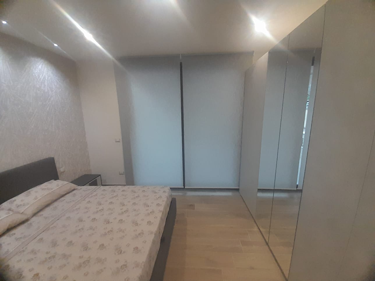 Camera da letto con ampio armadio a specchiera e finiture moderne