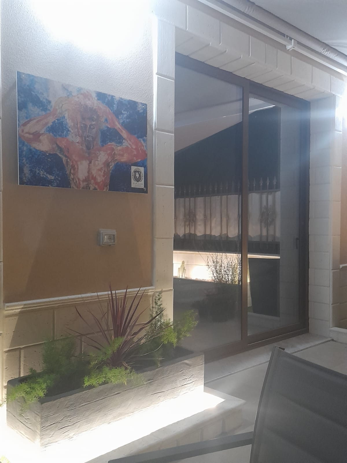 Interno della casa con opera d'arte alla parete e affaccio sul patio