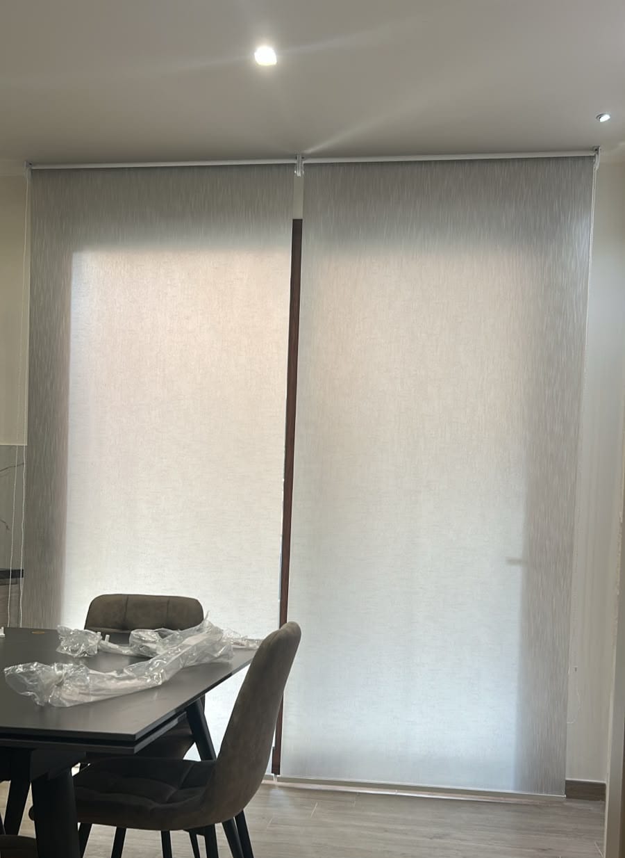 Zona pranzo accanto alla vetrata con tenda filtrante