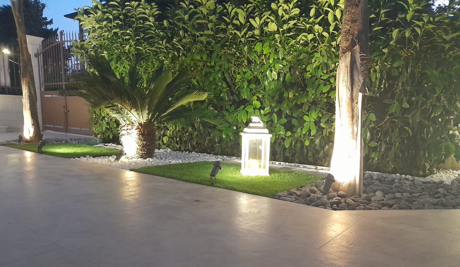 Il giardino privato illuminato al calar della sera, tra palme e piante esotiche