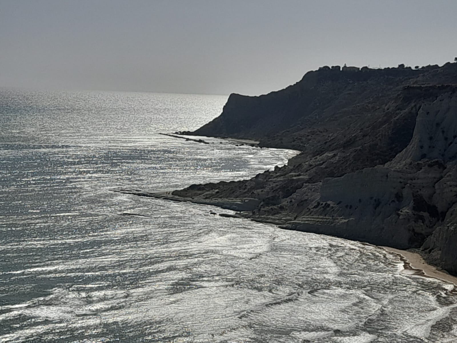 Riflessi d'argento sul mare ai piedi della falesia