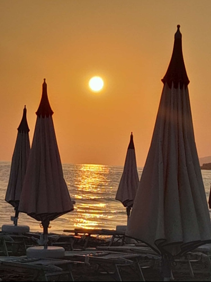 Ombrelloni in controluce al tramonto sulla spiaggia di Poliscia